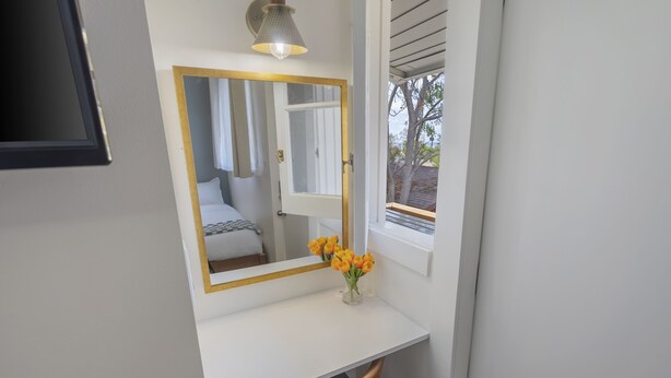 A white desk with a mirror, a vase with flowers, and a window with blinds. - 2 Bedroom Craftsman:KING Bed:Office:Views:Parking::Between Disney/Universal (Whittier)