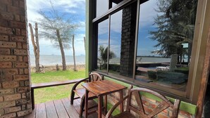 A wooden deck with a table and chairs, overlooking a beach and the sea. - The Chevalley beach resort  (Thung Wa)
