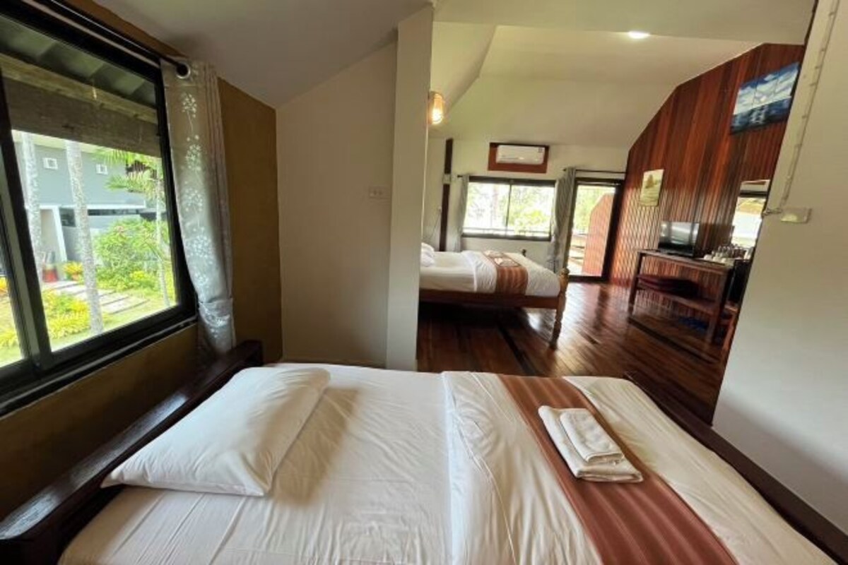 A hotel room with a bed, a TV, and a window with curtains.