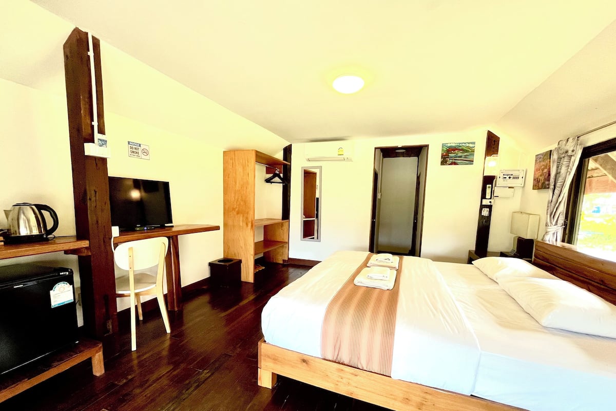A hotel room with a bed, a desk, a chair, a television, and a wardrobe.