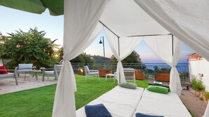 Ein privates Schlafzimmer im Freien mit zwei Betten, weißen Vorhängen und Meerblick.