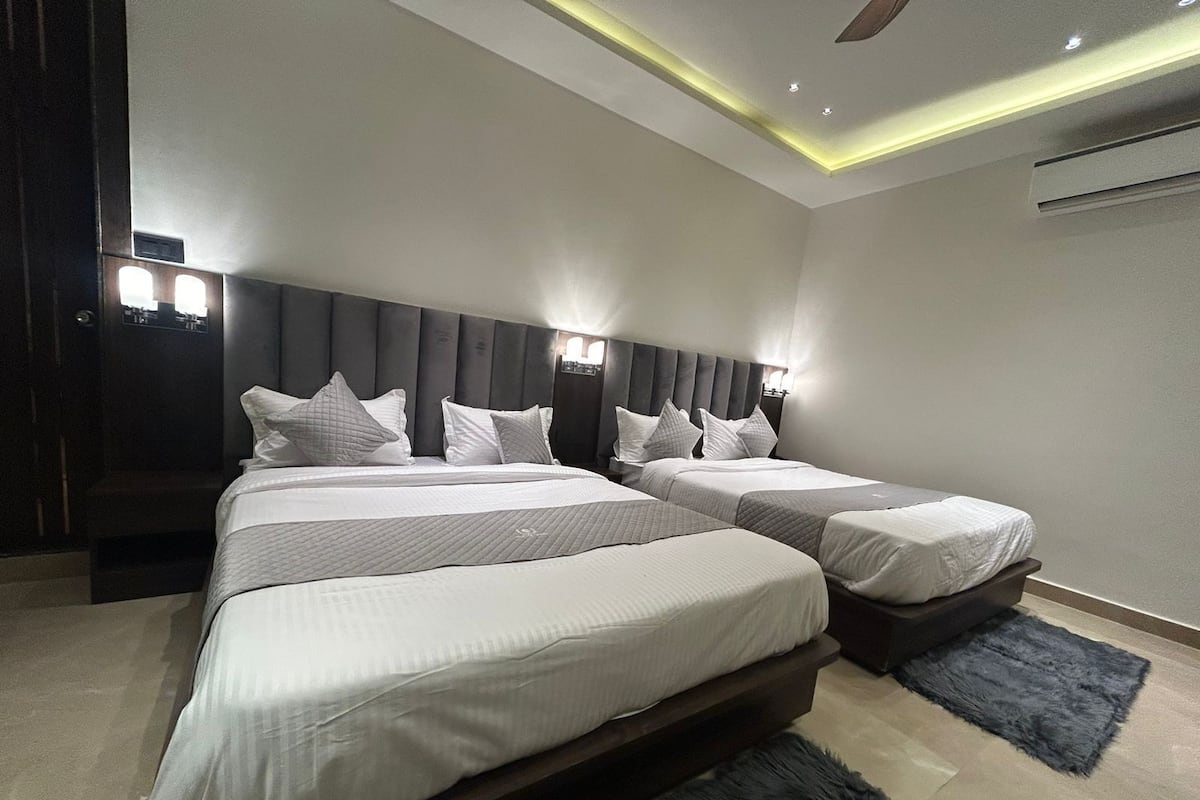 A modern hotel room with a large bed, a separate bed, and a desk.