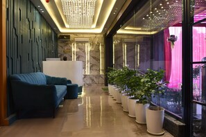 A reception area with a modern design, featuring a reception desk, seating area, and potted plants. - Hotel Majestic Grand By MNG Rooms (Kanpur)