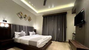 A modern hotel bedroom with a large bed, a flat-screen TV, and a ceiling fan. - Hotel Majestic Grand By MNG Rooms (Kanpur)