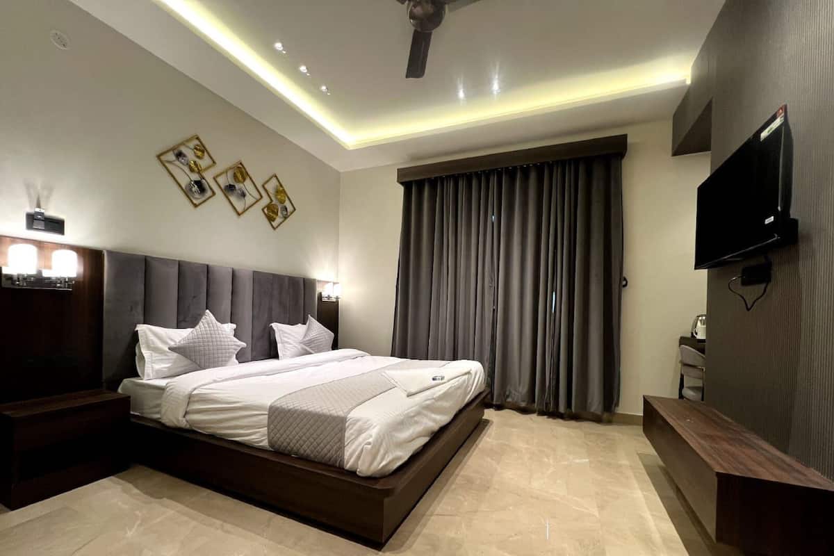 A modern hotel bedroom with a large bed, a flat-screen TV, and a ceiling fan.