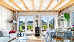 Ein gemütliches Wohnzimmer mit Kamin, Essbereich und großen Fenstern mit Blick auf den Garten.