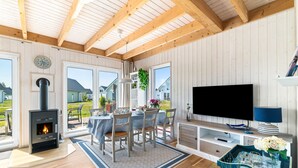 Ein gemütliches Zimmer mit Kamin, Esstisch, Stühlen und Fernseher.