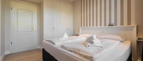 A hotel room with a large bed, a wardrobe, and a striped wall.