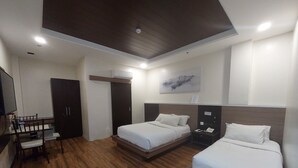 Een moderne hotelkamer met twee bedden, een bureau en een kledingkast.