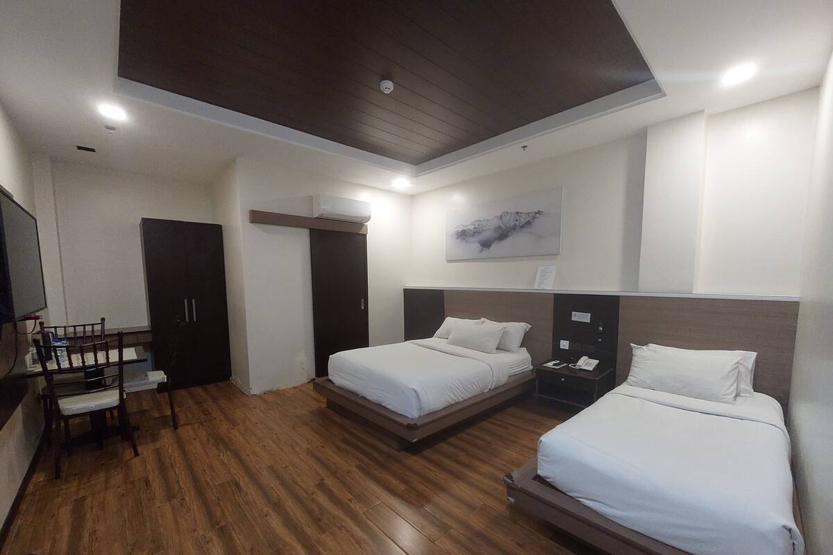 A modern hotel room with two beds, a desk, and a wardrobe.