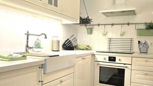 Una cocina compacta con muebles blancos, un lavamanos de acero inoxidable y un horno empotrado.