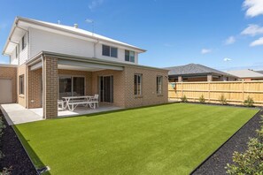 Ein modernes, zweistöckiges Haus mit Terrasse und einem gepflegten Rasen.