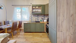 Una cucina compatta con mobili verdi, uno schienale piastrellato e un'area pranzo con tavolo e sedie.