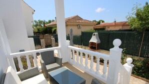 A balcony with wicker furniture, a glass table, and a white railing. - Beachside Oasis: Private Pool, Optional A/C, Free Wi-Fi, Pet Friendly, Near Dog Beach (Deltebre)