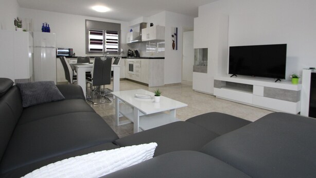A modern living room with a grey sofa, a white coffee table, and a flat-screen TV. - Beachside Oasis: Private Pool, Optional A/C, Free Wi-Fi, Pet Friendly, Near Dog Beach (Deltebre)