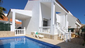 A swimming pool with a tiled edge, white lounge chairs, and a covered patio area with a staircase. - Beachside Oasis: Private Pool, Optional A/C, Free Wi-Fi, Pet Friendly, Near Dog Beach (Deltebre)