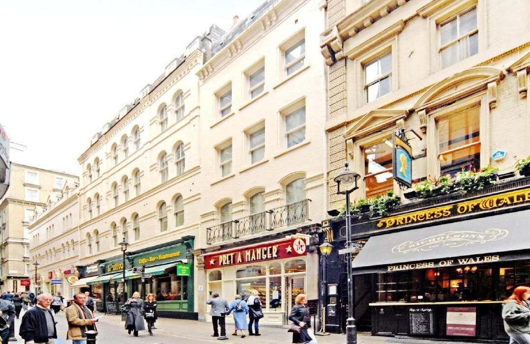 En gade med bygninger, herunder en 'Pret A Manger' og en restaurant 'Princess of Wales'.