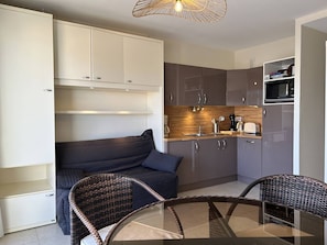 Enjoy a compact kitchenette with a microwave and coffee maker, adjacent to a cozy seating area with a sofa and two chairs.