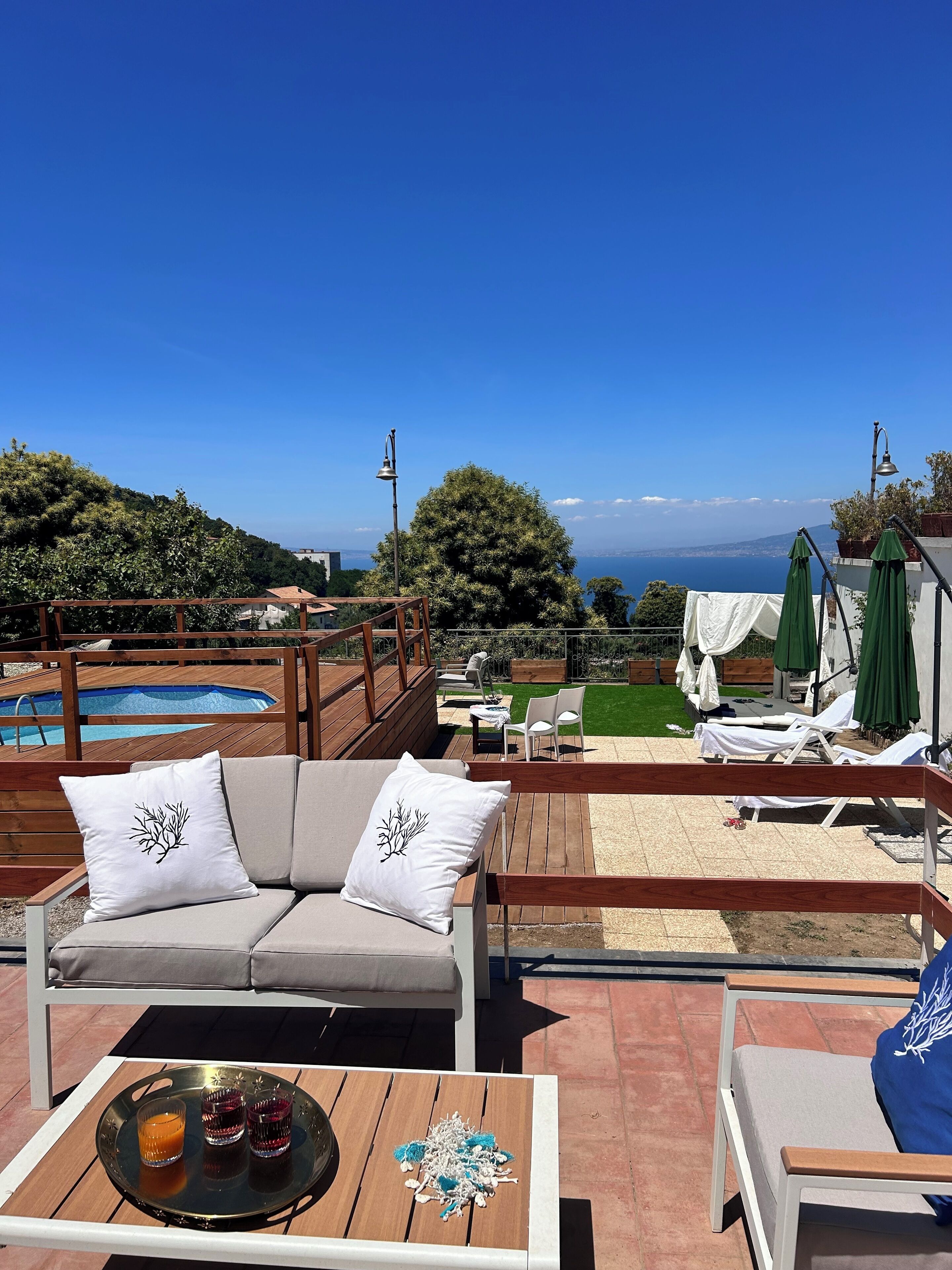 A rooftop terrace with a pool, lounge chairs, and a wooden deck.