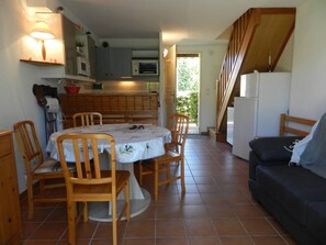 Cozy living space with a kitchen area, dining table, and comfortable seating area featuring a sofa and staircase to the upper level.