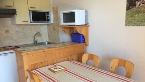 A compact kitchen with wooden cabinets, a microwave, a toaster, and a sink. - 2-room apartment for 5 people, Châtel, balcony, near center (Châtel)