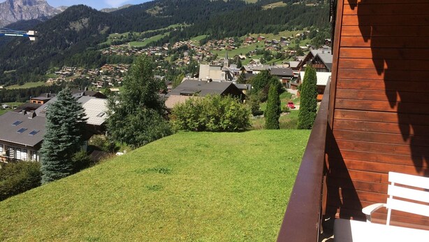 A hillside view of a village with houses, a church, and mountains in the background. - 2-room apartment for 5 people, Châtel, balcony, near center (Châtel)