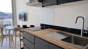 A modern kitchen with a wooden countertop, stainless steel sink, and black cabinets. - Renovated Studio with Balcony, A/C, Wi-Fi and Modern Amenities - 5 Min Walk to Thermes (Balaruc-les-Bains)