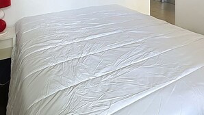 Uma cama com colchão e lençol brancos.