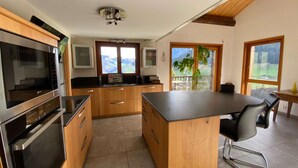 Una cocina moderna con armarios de madera, horno empotrado y una isla grande con encimera negra.
