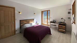 Un dormitorio con cama, escritorio, silla, ventana y puerta.