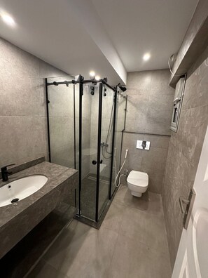 A modern bathroom with a glass-enclosed shower, a standalone sink, and a toilet. - Luxury Flat Stunning Nile View (Giza)