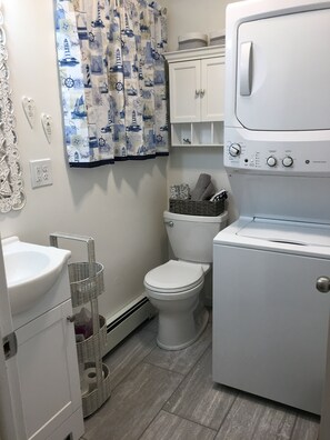 Une petite salle de bain comprenant des toilettes, un lavabo et un appareil combinant lave-linge et sèche-linge.