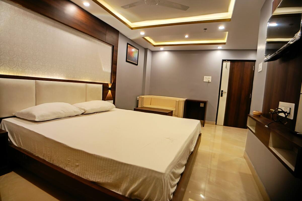 Ein modernes Hotelzimmer mit einem großen Bett, einem Nachttisch, einem Spiegel und einem Deckenventilator.