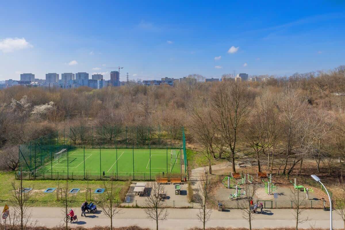 A park with a tennis court, exercise equipment, and a playground.