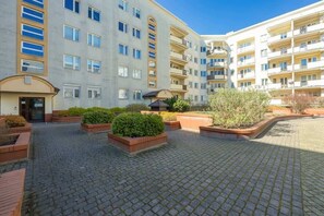 Un edificio residencial de varios pisos con un patio central que presenta macetas de ladrillo y plantas en macetas.