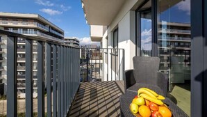 A balcony with a wicker chair and a fruit basket.