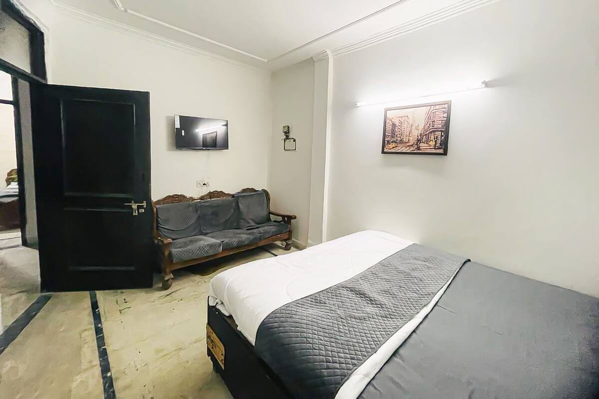 Un dormitorio con cama, sofá, televisión y un cuadro en la pared.