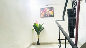 Un escalier avec une rampe noire, une plante en pot et un tableau encadré accroché au mur.