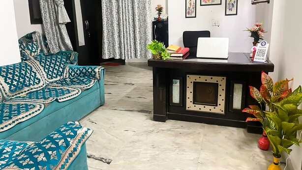 Un salon avec un canapé, un bureau avec un ordinateur portable et une porte au fond.
