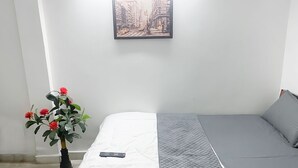 Une pièce avec un lit, une télécommande et un tableau encadré accroché au mur.