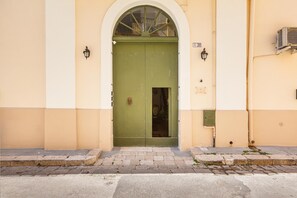 A green door with a small window, a number plate, and a wall-mounted air conditioning unit. - 3800 Case Aida - Celeste Superior 1P by Barbarhouse (Gallipoli)