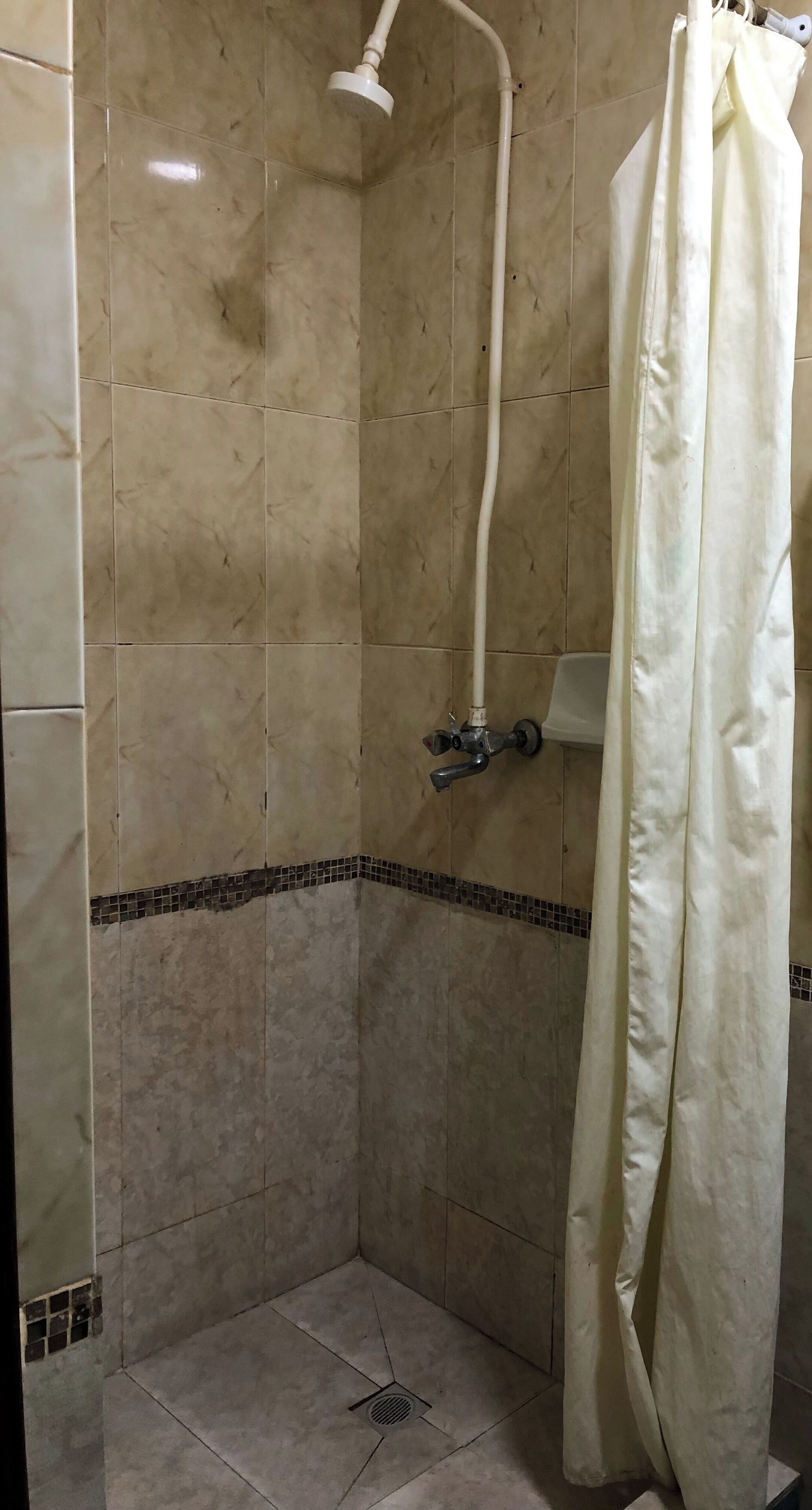 Ducha con cabezal de ducha de mano, cortina y pared de azulejos.