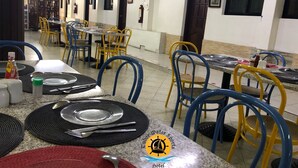Une salle à manger d'hôtel avec des tables disposées pour quatre personnes, des chaises et un buffet.