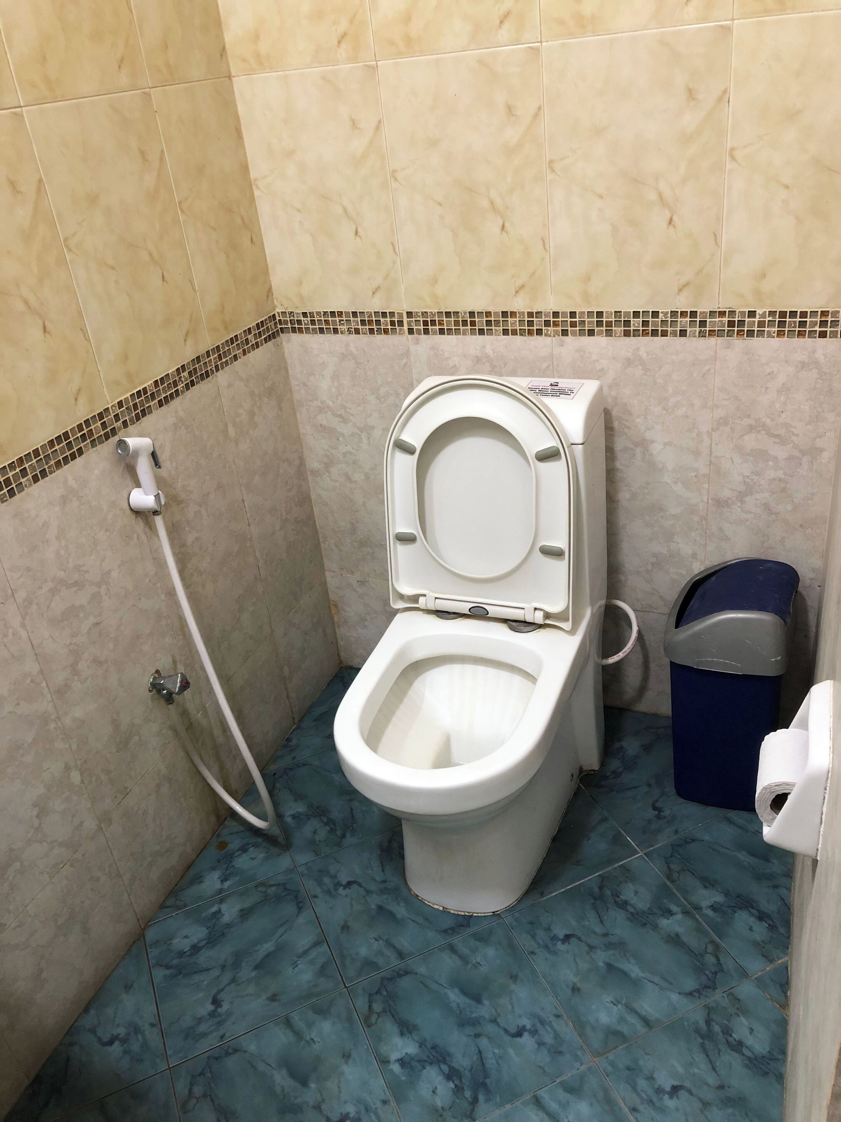 Un baño con inodoro, ducha y un cubo de basura.