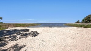 Una playa arenosa con un banco y una vista despejada del agua.