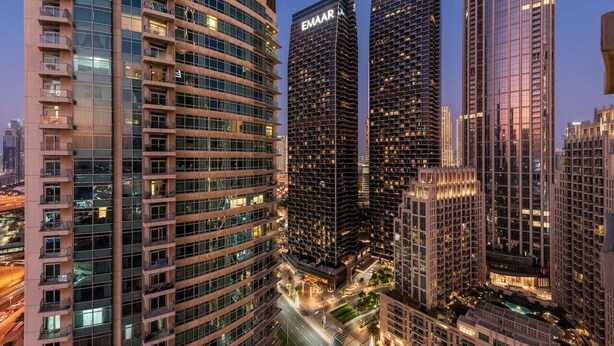 A high-rise building with multiple floors, large windows, and a prominent 'EMAAR' sign on the facade. - World Class | 2BR | Dubai Skyline & Sea view (Downtown)