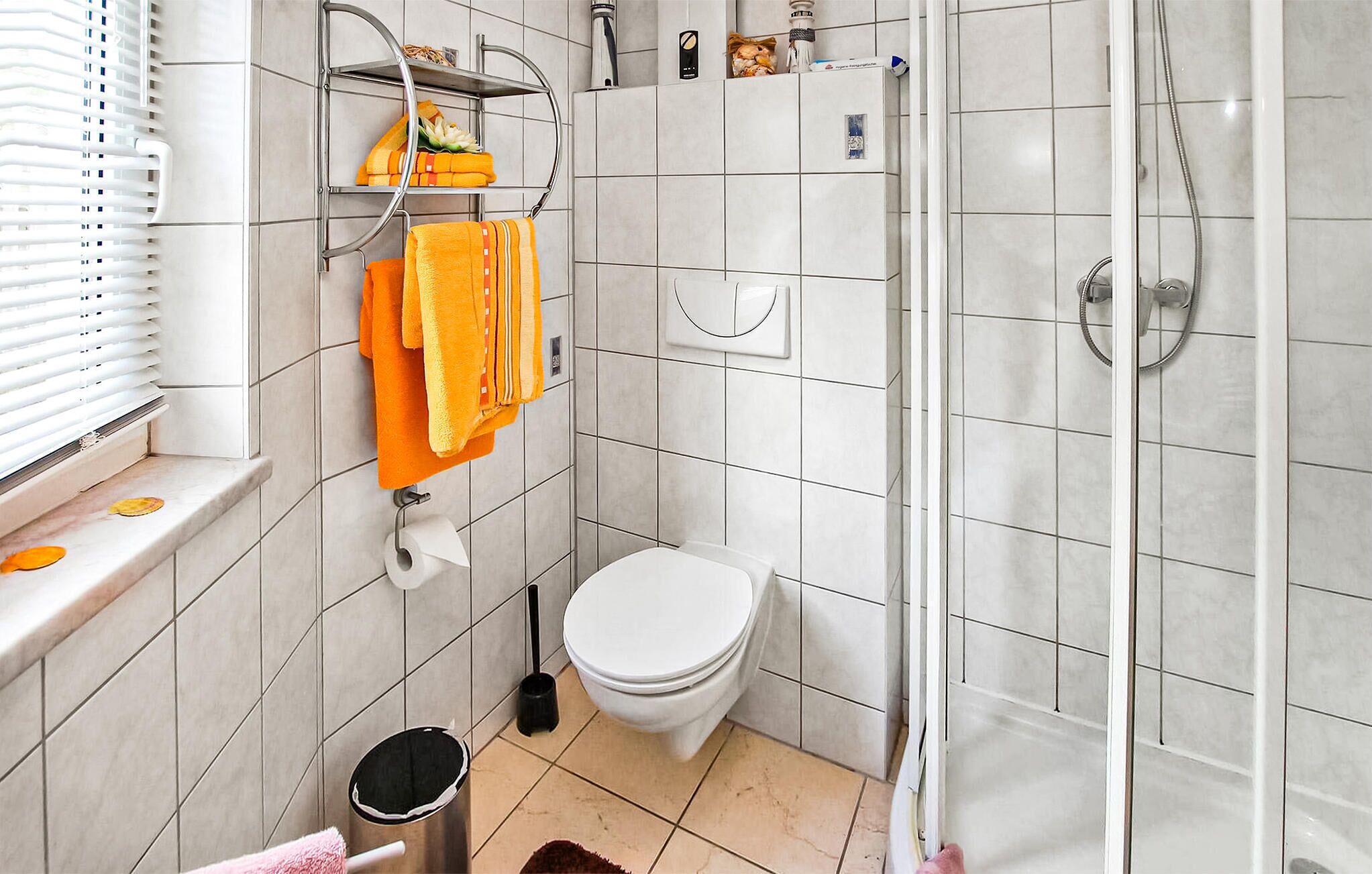 Une salle de bain équipée de toilettes, d’une douche et d’une étagère où sont rangées les serviettes.