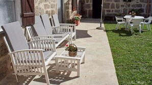 A patio with white furniture, including chairs and a table, and a potted plant.