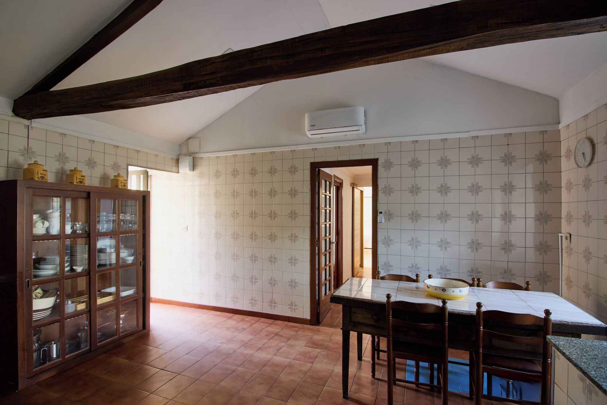 A dining area with a wooden table, chairs, and a cabinet with glass doors.