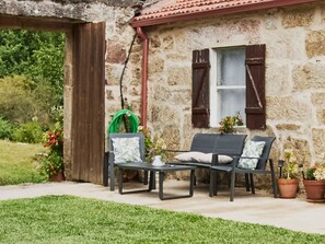 A stone building with a window, a door, and a small outdoor seating area with a table and two chairs. - THE HOUSE OF MILA (Crecente)
